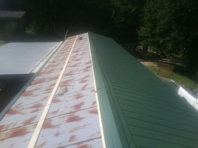 Old rusted panels beside newly installed green metal roofing — Wind Damage Roof Repair by Roofing Brothers in Winter Park