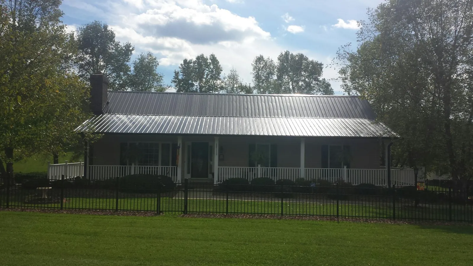 Gray metal roof on a brick ranch with a full width front porch — Gutter Guard Installation work by our crew in Winter Park