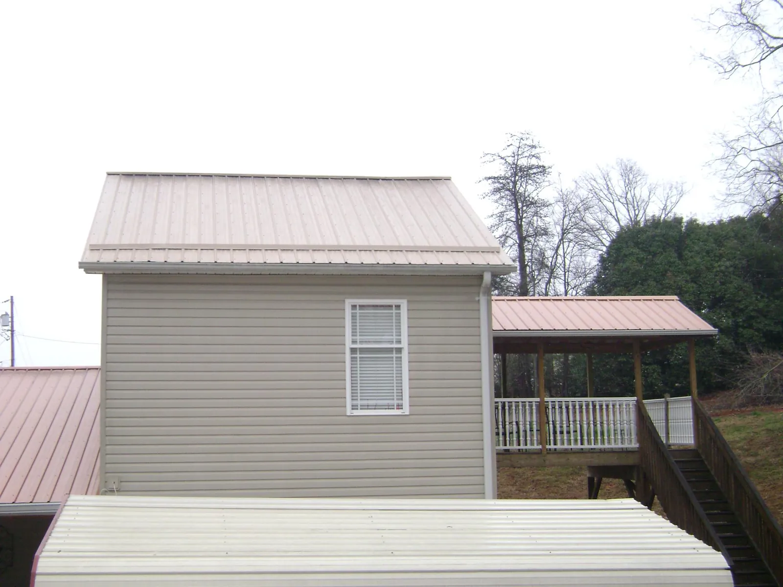 Tan metal roofs on a two story addition and attached porch, from a Roof Replacement job in Winter Park